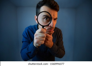 Surprised Young man student holding magnifying glass looking to camera with a pensive emotion isolated over grey  background. Science and curiosity concept.  - Shutterstock ID 1560996377