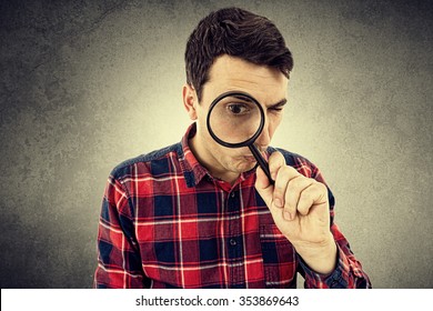 Surprised Young man student holding magnifying glass looking to something isolated over white background.