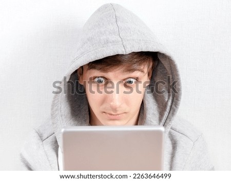 Surprised Young Man with a Tablet Computer on the White Wall Background closeup