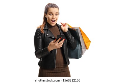 Surprised young woman with shopping bags looking at her mobile phone isolated on white background
