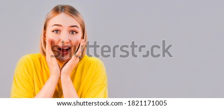 Surprised young woman smiling in studio isolated on gray background