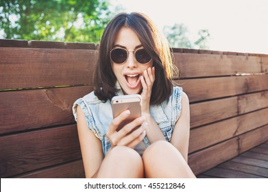 Surprised Young Woman Using Smart Phone Outdoors