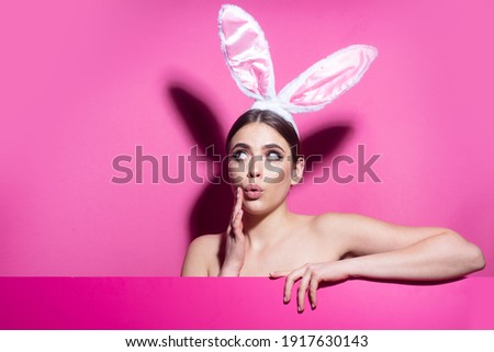 Surprised young woman wearing rabbit ears isolated on pink