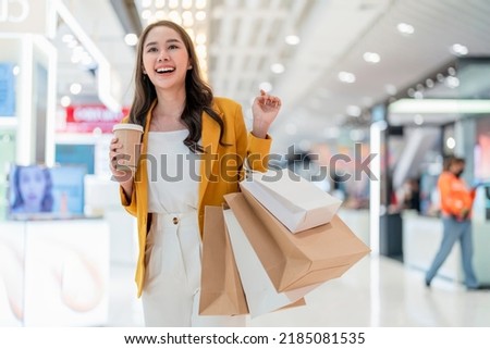surprising cheerful asian female adult woman shopper hand hold shopping bag and coffee paper cup walking buying cloths in department store shopping mall with happiness exited toothy smiling joyful