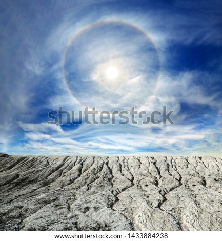 Surreal fantasy extraterrestrial landscape. Digitalart artwork. Sun halo in the blue sky around the sun over the white cracked mountains. Natural phenomenon