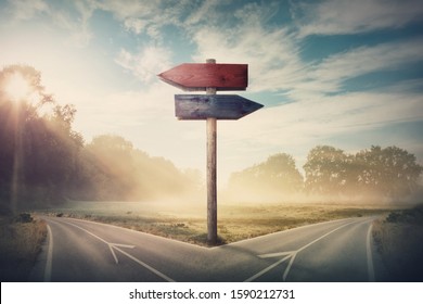 Surreal landscape with a split road and signpost arrows showing two different courses, left and right direction to choose. Road splits in distinct direction ways. Difficult decision, choice concept. - Shutterstock ID 1590212731