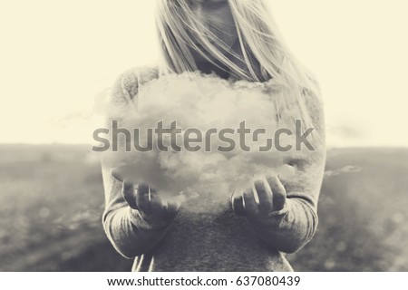 Surreal moment, solitary woman holding in her hands a gray cloud