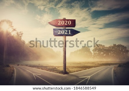 Surreal scene with a split road and signpost arrows showing two different courses, left and right, past and future, old 2020 and the new 2021 year direction to choose. Life decision, choice concept.