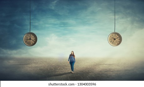Surreal scene young woman walking on a pavement road and two suspended clocks on her back hanging from the sky showing different hour. Time travel concept.  