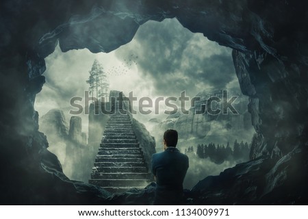 Surreal view as a man escape from a dark cave stand in front of a mystic stairway crossing the misty abyss going up to unknown paradise. Opportunity staircase, exit way to success, freedom concept.