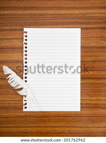 Surrender note with white feather. Lined torn sheet of paper, blank for your message. On desk.