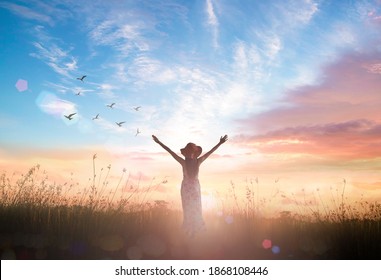 Surrender and praising concept: Silhouette of healthy Christian woman raised hands at meadow sunset background - Powered by Shutterstock