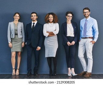 Surrounded by business minded individuals. Studio shot of a group of businesspeople standing in line against a gray background. - Shutterstock ID 2129308205