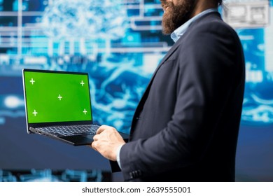 Surrounded by data and neural networks systems, male IT engineer navigates artificial intelligence with a chroma key on laptop. Using automation for modern strategy and innovation.