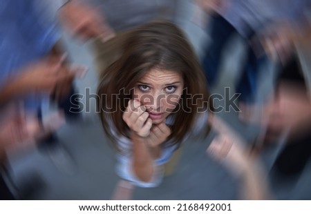 Surrounded by self-doubt. Conceptual shot of an anxious young woman in the middle of a circle of accusing coworkers.