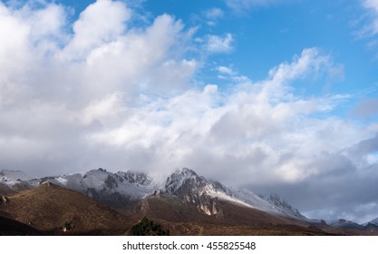 Surrounded by snow-capped mountains clouds peak.