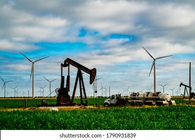 Surrounded by Wind Turbines and Oil Pump in West Texas display the Old and the New of Energy consumption , Climate Change , and the fight for Renewable Energy. Old oil tanker sits in green grass field