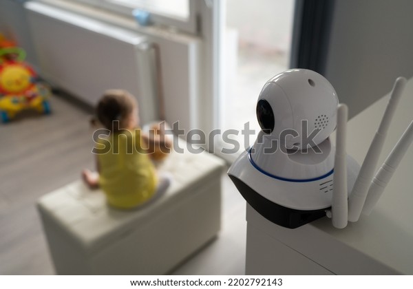 Surveillance camera baby monitor at home\
monitoring small child while playing in room childhood family\
protection parenthood\
concept