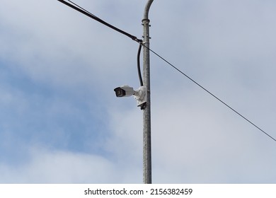 Surveillance camera on a metal pole on a background of sky. 