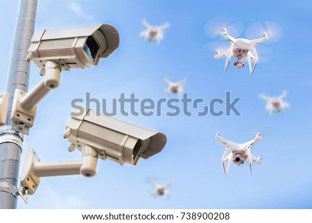 Surveillance Cameras On Pole With Drones Flying In The Blue Sky