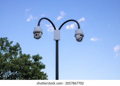 Surveillance Cctv (closed Circuit Television) Camera Installed In Public Park On Blue Sky Background For Protection Against Crime, Observation Of People, Control Of Observance Of Public Order.