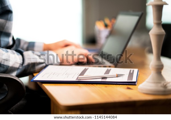 Survey\
form, customer satisfaction feedback poll, resume for job\
application or for college. Man writing with laptop.  Home or car\
insurance contract. Paper sheet and pen on\
desk.