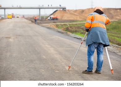 Surveyor engineer worker making measuring with theodolite equipment at construction site during road works