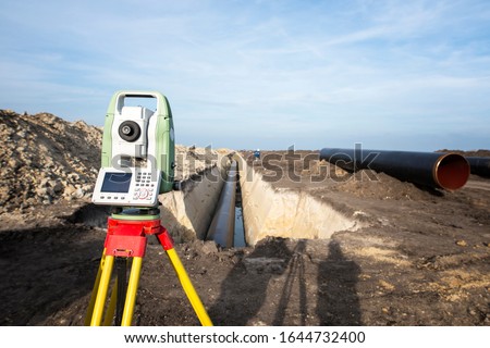 Surveyor GPS system equipment at pipeline construction. Civil engineers surveyors measuring coordinates to precisely lay down pipe tubes for gas distribution in the ground.