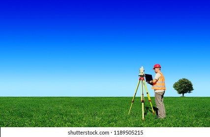 Surveyor on green field, blue sky in background