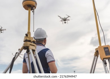 A surveyor operating a drone to conduct topographic RTK or PPK aerial survey or photography of a site. A GNSS receiver is visible in front.
