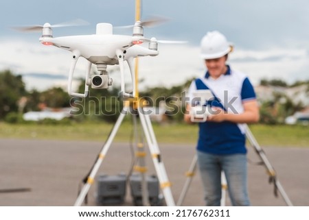 A surveyor operating a drone to conduct topographic RTK or PPK aerial survey or photography of a plot of land.