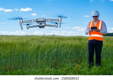 Surveyor with quadrocopter. Geodetic research before construction. Man in work uniform admits quadcopter. Modern geodetic drone. Surveyor quadcopter over field of grass. Surveyor services. Art focus