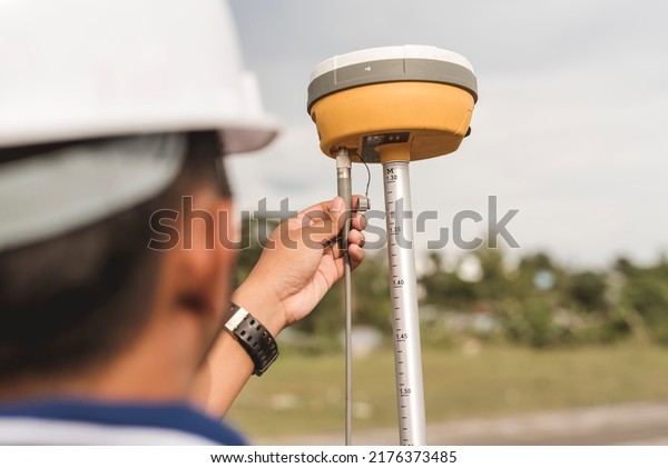 A surveyor sets up a Global Navigation\
Satellite System or GNSS Receiver. Real-time kinematic or RTK\
geodetic surveying equipment used in the\
field.