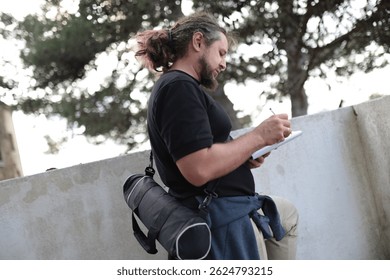 Surveyor taking notes outdoors with notepad and pencil