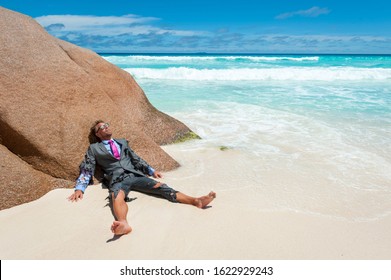 Survivor castaway businessman washed up on a tropical beach in a ragged torn suit - Shutterstock ID 1622929243