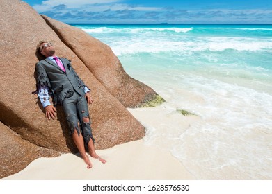 Survivor castaway businessman washed up on a tropical beach in a ragged torn suit - Shutterstock ID 1628576530