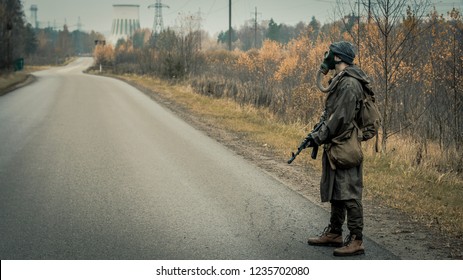 Survivor Soldier In Gas Mask And With Russian Assault Rifle Walking In The Danger Radioactive Zone Of Wastelands. Post Apocalypse. Nuclear War.