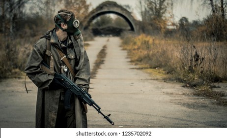 Survivor Soldier In Gas Mask And With Russian Assault Rifle Walking In The Danger Radioactive Zone Of Wastelands. Post Apocalypse. Nuclear War.