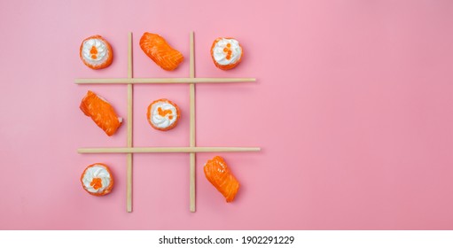 Sushi ansd sushi rolls set with salmoln. Tic tac toe concept idea. Sushi rolls on pink minimalistic background