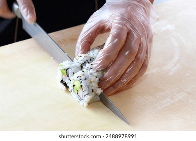 Sushi chef rolls and cuts sushi rolls - Powered by Shutterstock