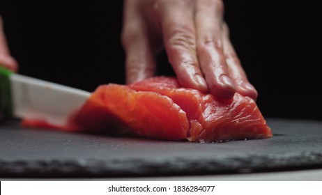 Sushi Chef Slices fresh Salmon on the sushi bar. Chef cutting salmon fillet at professional kitchen. Closeup chef hands slicing fresh fish slice in slow motion. Professional man cutting red fish - Powered by Shutterstock