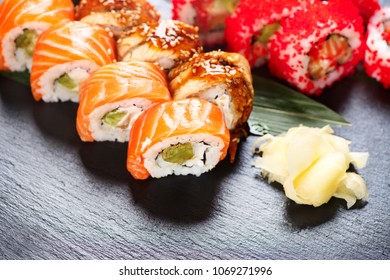 Sushi with chopsticks. Sushi roll japanese food in restaurant. California Sushi roll set with salmon, vegetables, flying fish roe and caviar closeup. Japan restaurant menu