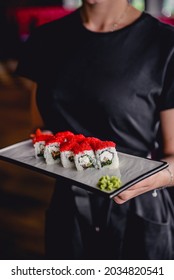 Sushi With Cream Cheese And Red Caviar On Top Served On A White Plate By Waiter In Restaurant. Japanese Cuisine Concept. Waiter Service.