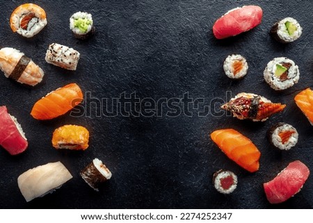 Sushi frame, overhead flat lay shot. Rolls, maki, nigiri on a black slate background, Japanese food. Salmon, eel, shrimp, tuna etc with rice, with copy space