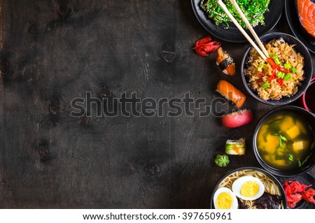 Sushi and japanese food on dark background. Sushi rolls, hiyashi wakame, miso soup, ramen, fried rice with vegetables, nigiri, soy sauce, chopsticks. Asian/Japanese food frame. Overhead



