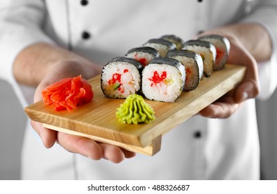 Sushi master holding wooden board with delicious sushi set
