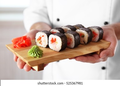 Sushi master holding wooden board with delicious sushi set