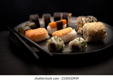 Sushi on black plate with black chopsticks dark background - Shutterstock ID 2150510959