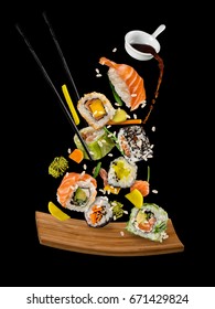 Sushi pieces placed between chopsticks, separated on black background. Popular sushi food. Very high resolution image
