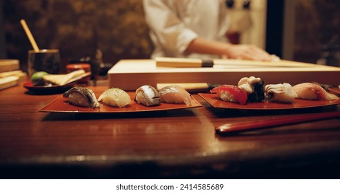 Sushi, plate and serving with chef in restaurant for luxury cuisine or raw meal preparation closeup. Kitchen, food and presentation with person cooking local Japanese seafood for service in Tokyo - Powered by Shutterstock